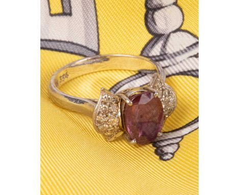 An 18K white gold ruby and diamond ring, the oval ruby approximately 9mm x 6mm, flanked by diamond set shoulders, size N, app