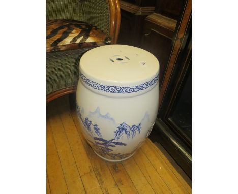 An oriental blue and white ceramic garden seat, decorated with a mountain scene 