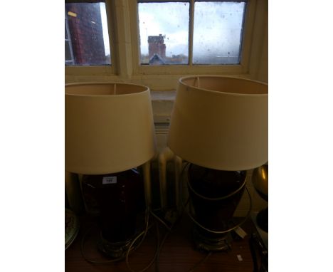 A pair of red glazed octagonal ceramic table lamps, raised on sliver-plated bases with fitted fabric shades (sold electricall