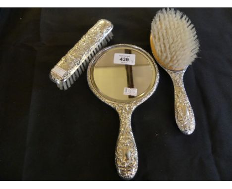 A silver backed three piece dressing table brush and mirror set, decorated with cherubs 