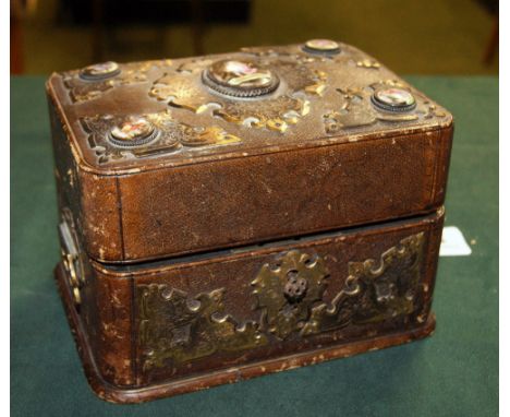 A scent caddy of six glass flasks, the case bound in leather with gilt metal mounts and having small limoges style panels. 