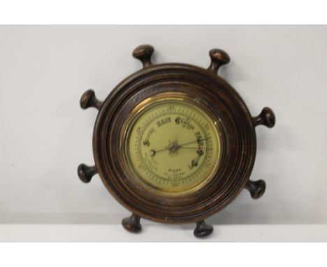 A vintage oak framed barometer in the form of a ships wheel 