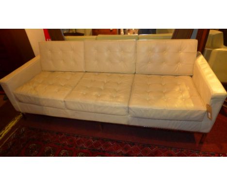 A Florence Knoll style sofa upholstered in ivory buttoned faux leather on chromed supports  