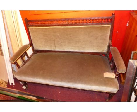 An Edwardian walnut sofa upholstered in green velour and raised on turned supports 