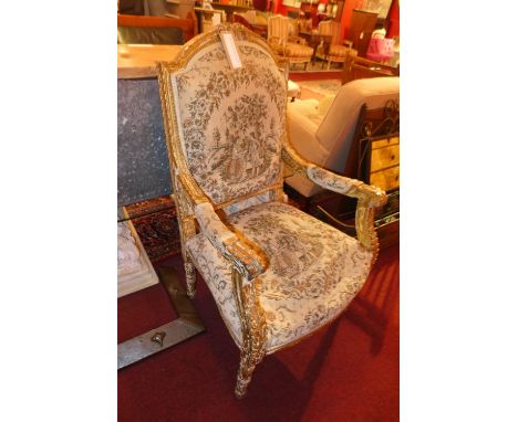 A French carved giltwood armchair upholstered in tapestry fabric and raised on fluted supports 