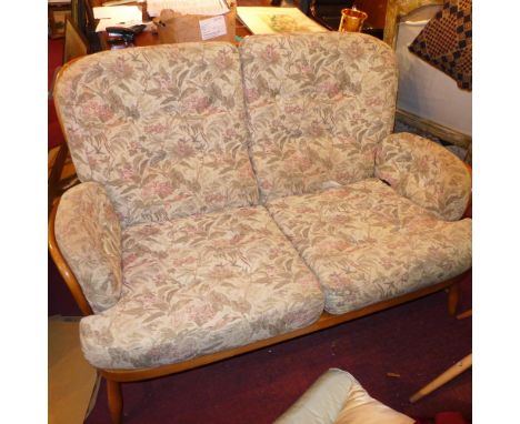 An Ercol two seater sofa, and an Ercol armchair with floral, upholstered cushions 