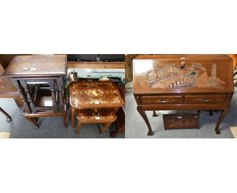 A mid 20th century bureau with carved Oriental scenes, together with a matching magazine rack, nest of tables and an occasion