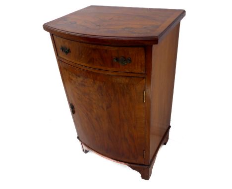 An early 20th century bow-fronted&nbsp;side cabinet in&nbsp;figured mahogany: the crossbanded overhanging moulded top above a