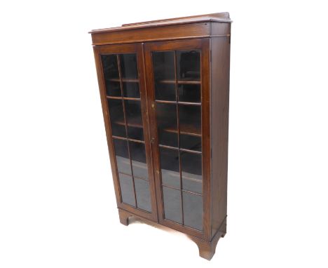 An early 20th century oak display cabinet / bookcase: the galleried top above two glazed doors with geometric astragal glazin