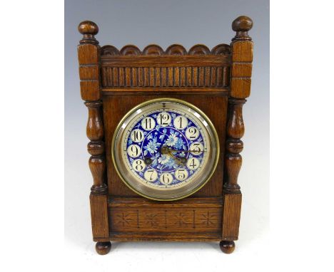 An Aesthetic Movement oak mantel clock, in the style of J.W. Benson, with blue floral enamel painted ceramic dial and twin wi