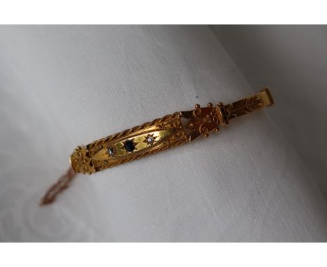 A 15ct yellow gold hinged bangle set with a central sapphire and two diamonds to a wire work and ball decorated top, approxim