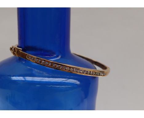 A 9ct gold hinged bangle set with twenty five round brilliant cut diamonds, approximately 11 grams