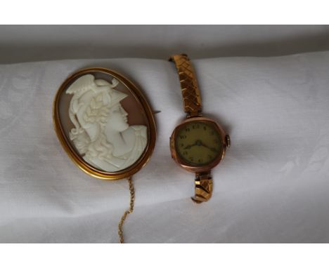 A lady's 9ct yellow gold wristwatch with a circular dial on an expanding bracelet strap, together with a shell cameo brooch d