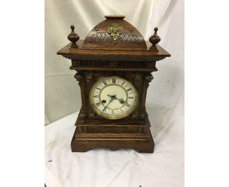 An orante mantel clock in an oak case