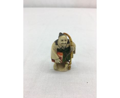 A Meiji Period Ivory netsuke of a man with a rod and box, coloured in green and yellows