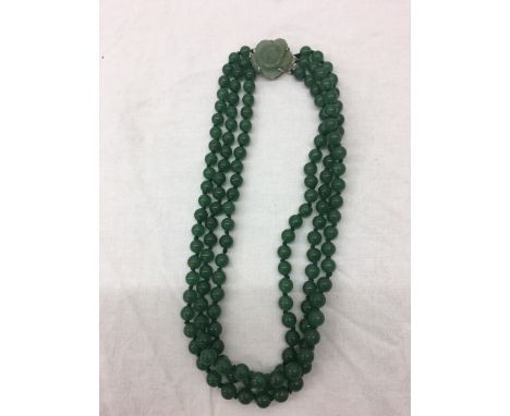 A jade three-strand bead necklace with carved floral jade clasp