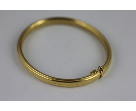 An 18ct yellow gold bangle, of ribbed design with integral clasp and single safety catch, total weight 16.4gms 