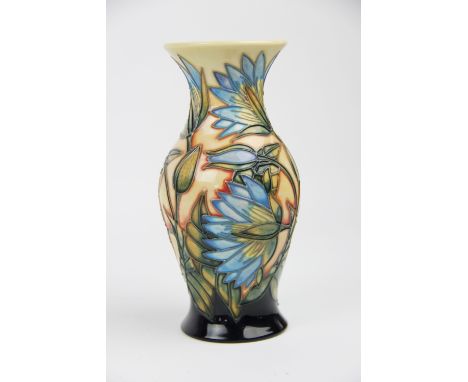 A limited edition Moorcroft tubed lined vase of fluted form decorated with blue flowers upon an orange ground, impressed and 