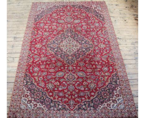 A large Persian wool Kashan carpet, worked wit a three section medallion against an overall floral red ground,  330cm x 211cm