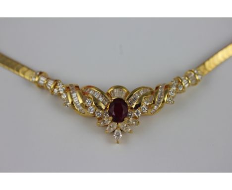 A ruby and diamond set necklace in 18k yellow gold, designed as a central oval ruby within a diamond set scroll surround, set