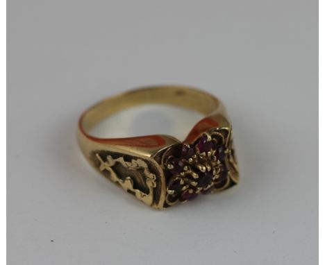 A ruby set gold dress ring, designed as a central floral cluster in decorative surround stamped '9ct', weight 7.7gms