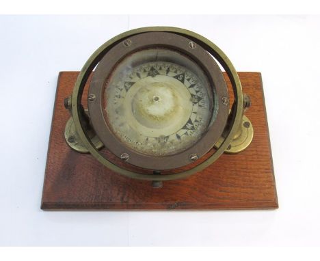 An early-mid 20th Century brass gimbaled compass mounted onto an oak plinth