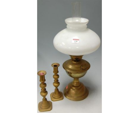 An early 20th century glass oil lamp with opalescent shade together with a pair of turned brass candlesticks (3)