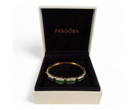 An 18ct gold diamond and emerald bangle - the pave set stones flanked by diamonds, 20.5g.