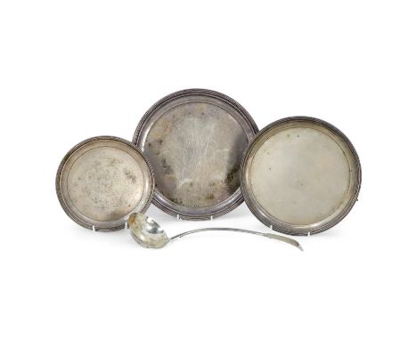 Three graduated silver plated waiters - circular with beaded rims and raised on ball and claw feet, together with a ladle. (4