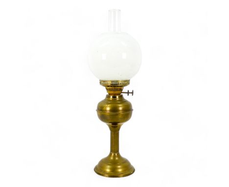 An early 20th century brass oil lamp - with a milk glass globe shade, with a fluted column, 57cm high.