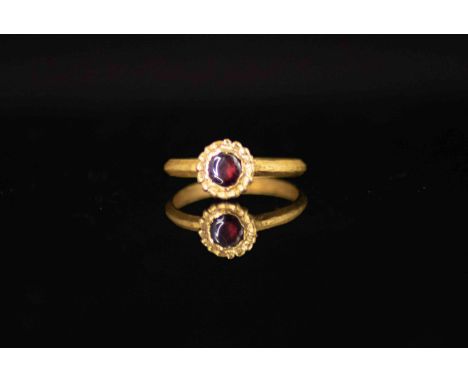 Roman Gold Ring with Cabochon Garnet2nd – 3rd Century AD.A gold ring with thin band and circular bezel with cabochon garnet.E