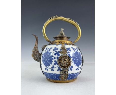 A Chinese blue and white porcelain teapot, of ovoid form with gilt metal loop handle, spout and mounts, the body with floral 