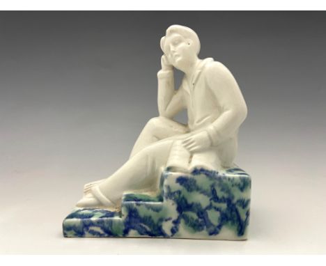 An Art Deco figural bookend, circa 1930, modelled as a sitting man in pyjamas with books, on a stepped sponge marbled base, 1