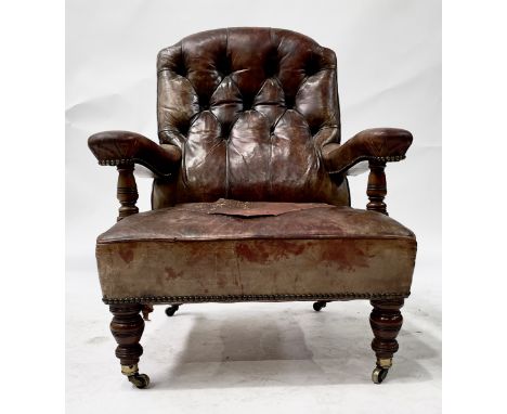 A Victorian mahogany library armchair, circa 1870, worn red leather button back upholstery, studded arms and seat, ring turne