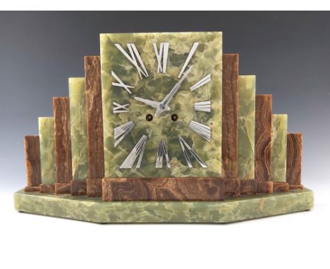 An Art Deco onyx mantel clock, chrome numeral clockface flanked by stepped brown and green onyx slabs, on angular green marbl