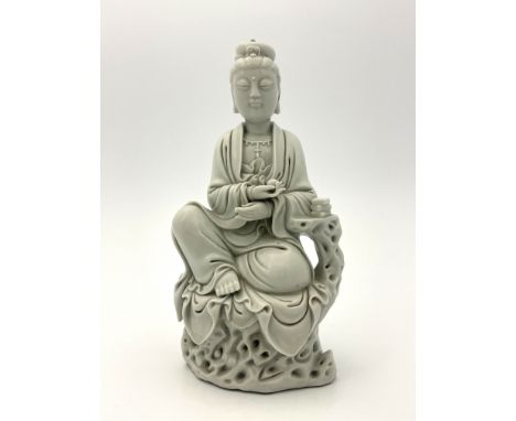 A Chinese blanc de chine figure of Guanyin, bears the impressed mark of 'seal of He Chaozong', modelled sitting on a rocky ou