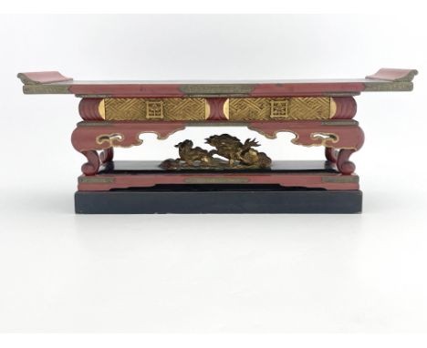 A Chinese black and red lacquer stand, early 20th Century, raised on scroll feet upon a double plinth with a carved gilt frie