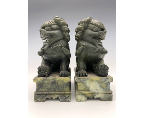 A pair of Chinese carved stone shishi guardian lions, modelled with mouths open, each with one paw resting on a cub or ball, 