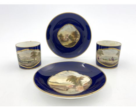 A pair of Derby Bloor coffee cans and saucers, circa 1830, each painted with a vignette landscape view in a gilt quatrefoil b