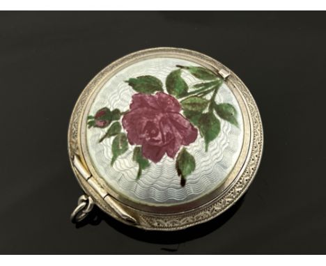 An Imperial Russian silver and enamelled compact, Moscow circa 1890, lens form, the lid with painted rose over pale blue guil