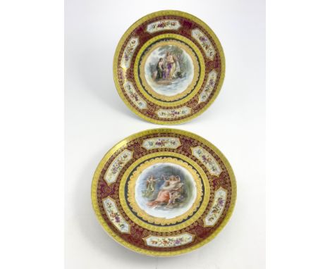 A pair of late 19th Century Vienna porcelain circular concave plaques, over-painted transfer classical maiden and cherub scen