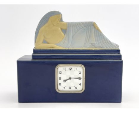 An Art Deco faience clock, circa 1925, cuboid form, the pediment modelled in relief as a reclining woman above a chequerboard