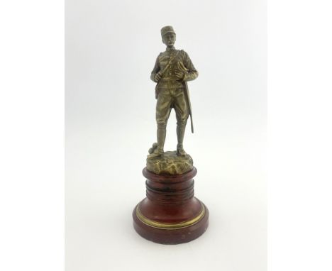 Georges Omerth, a bronze figure of a soldier, circa 1900, modelled in uniform next to a stack of canonballs, on turned red ma