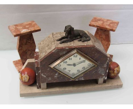A French Art Deco marble mantel clock and garniture, surmounted by a recumbent dog