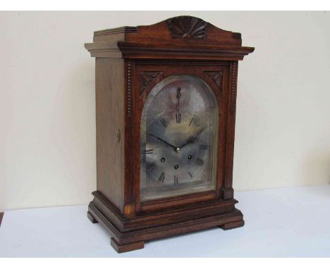 A late 19th Century oak cased bracket clock of architectural form, silvered Roman arched dial with three train movement, chim