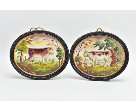 A PAIR OF 19TH CENTURY STAFFORDSHIRE POTTERY PLAQUES OF OVAL FORM, moulded in relief with a cow facing left and a bull facing