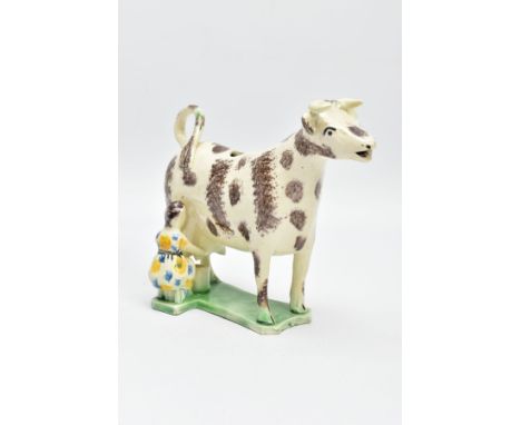 AN EARLY 19TH CENTURY STAFFORDSHIRE OR YORKSHIRE PEARLWARE COW CREAMER, modelled with a seated milkmaid, lacks cover, sponge 