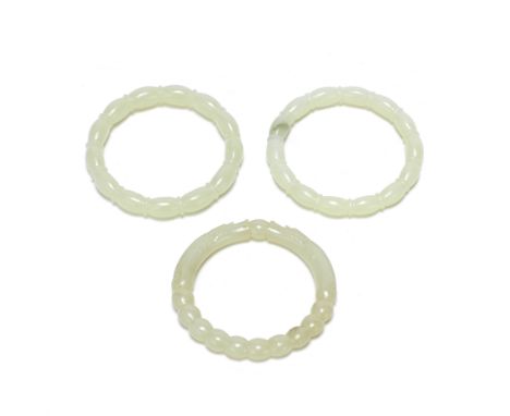 A GROUP OF THREE PALE JADE BANGLESComprising a pair of shaped ones; and a single 'dragons and flaming pearl' bangle. Each 7.5