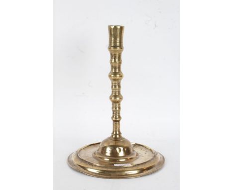 17th Century brass candlestick, circa 1660, the flared sconce above a knopped stem and dished foot, 31cm high, 22cm diameter