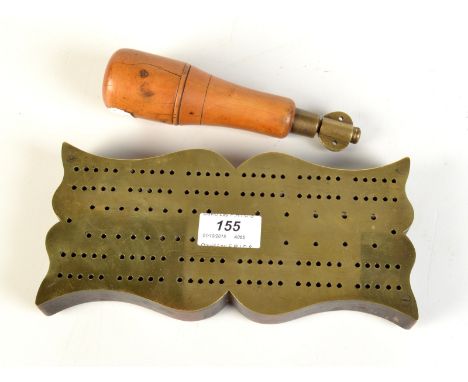 A shaped brass cribbage board on a hardwood base with sliding brass marker store cover, together with a clay "Churchwarden" p